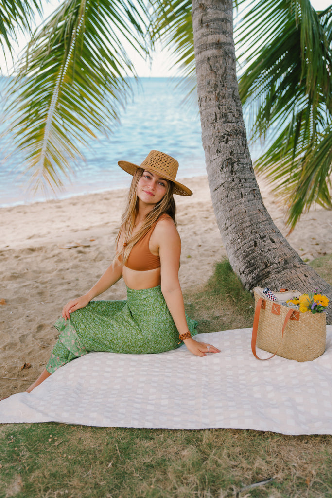 Person sitting on EHA Culture Magnolias & Gingham Luxurious Beach Towel